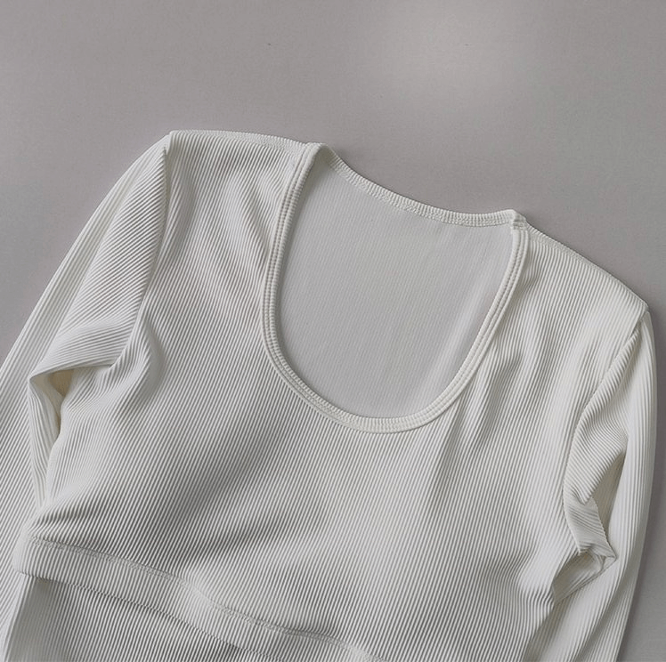 White women's yoga top with long sleeves and ribbed texture, featuring enhanced breathability and moisture-absorbing technology.